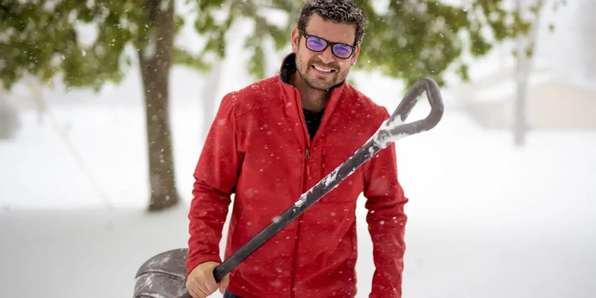 Smiling Buffalo, NY landscaper holding snow shovel, offering reliable snow removal services for harsh winter conditions
