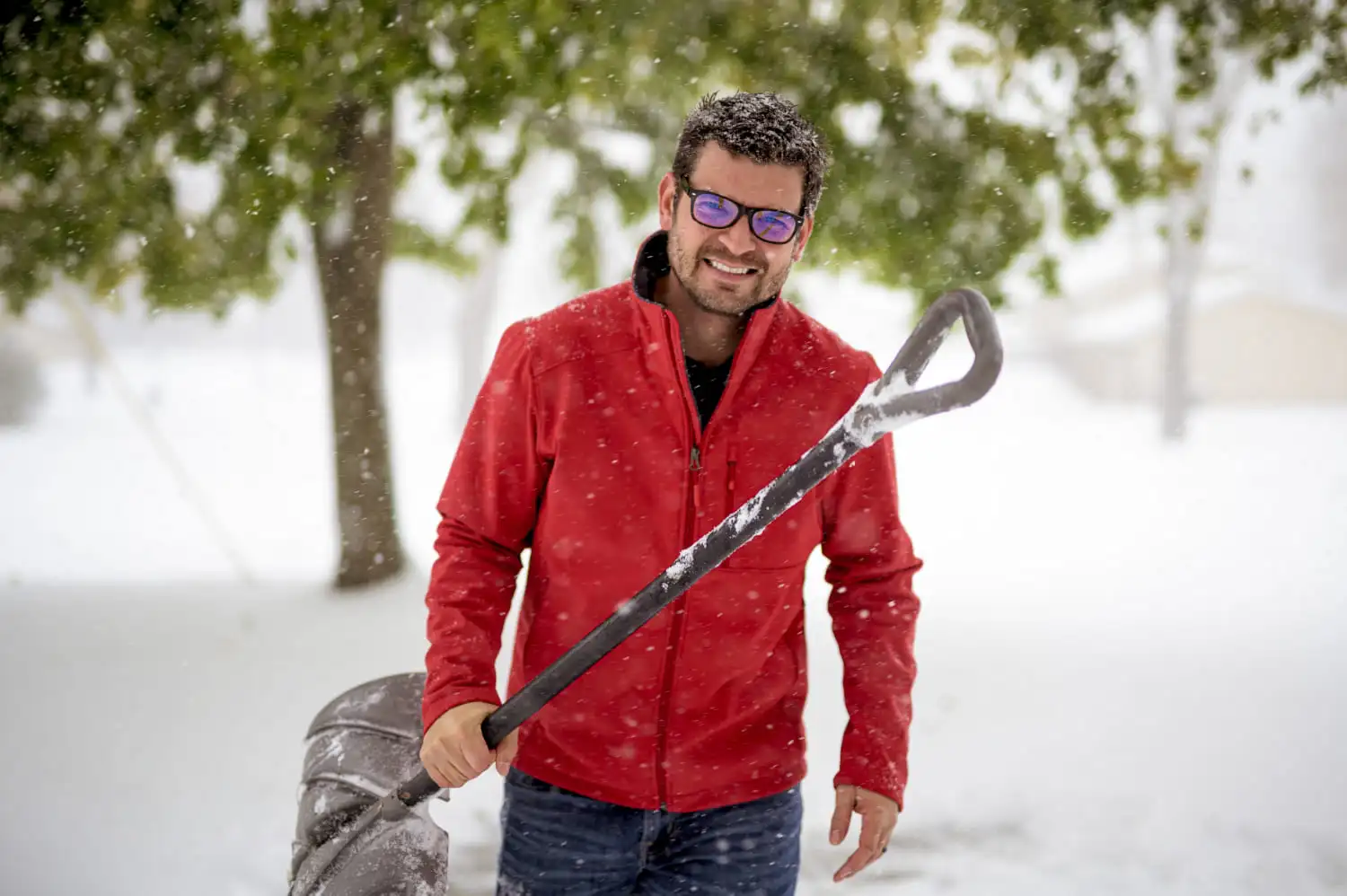 Smiling Buffalo, NY landscaper holding snow shovel, offering reliable snow removal services for harsh winter conditions