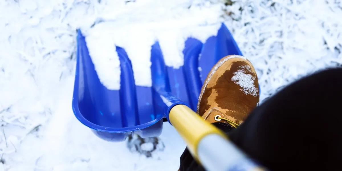 Close-up of Buffalo landscaper in uniform shoveling snow, emphasizing reliable snow removal services