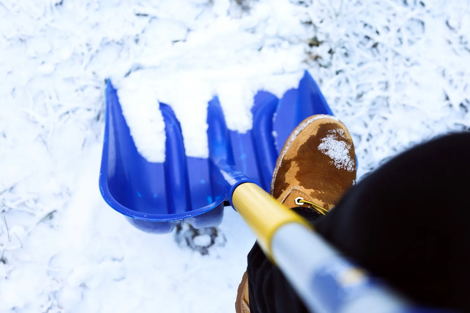Close-up of Buffalo landscaper in uniform shoveling snow, emphasizing reliable snow removal services